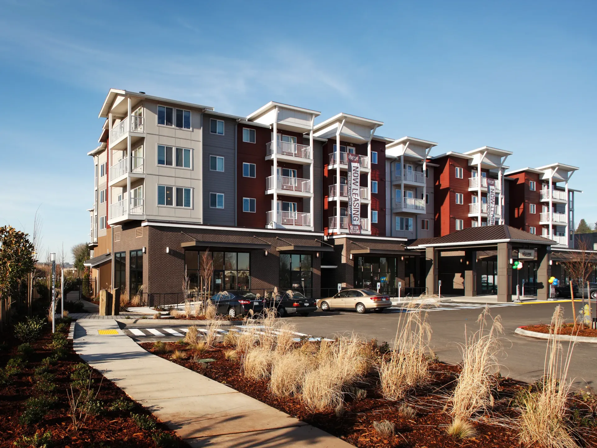 Exterior view of a modern multi-story apartment building with balconies, parking, and landscaping.