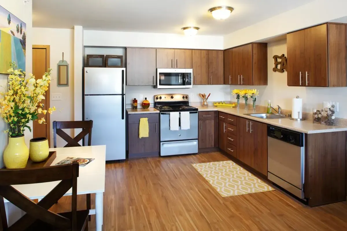 Open-concept apartment kitchen with stainless steel appliances and a small dining table.