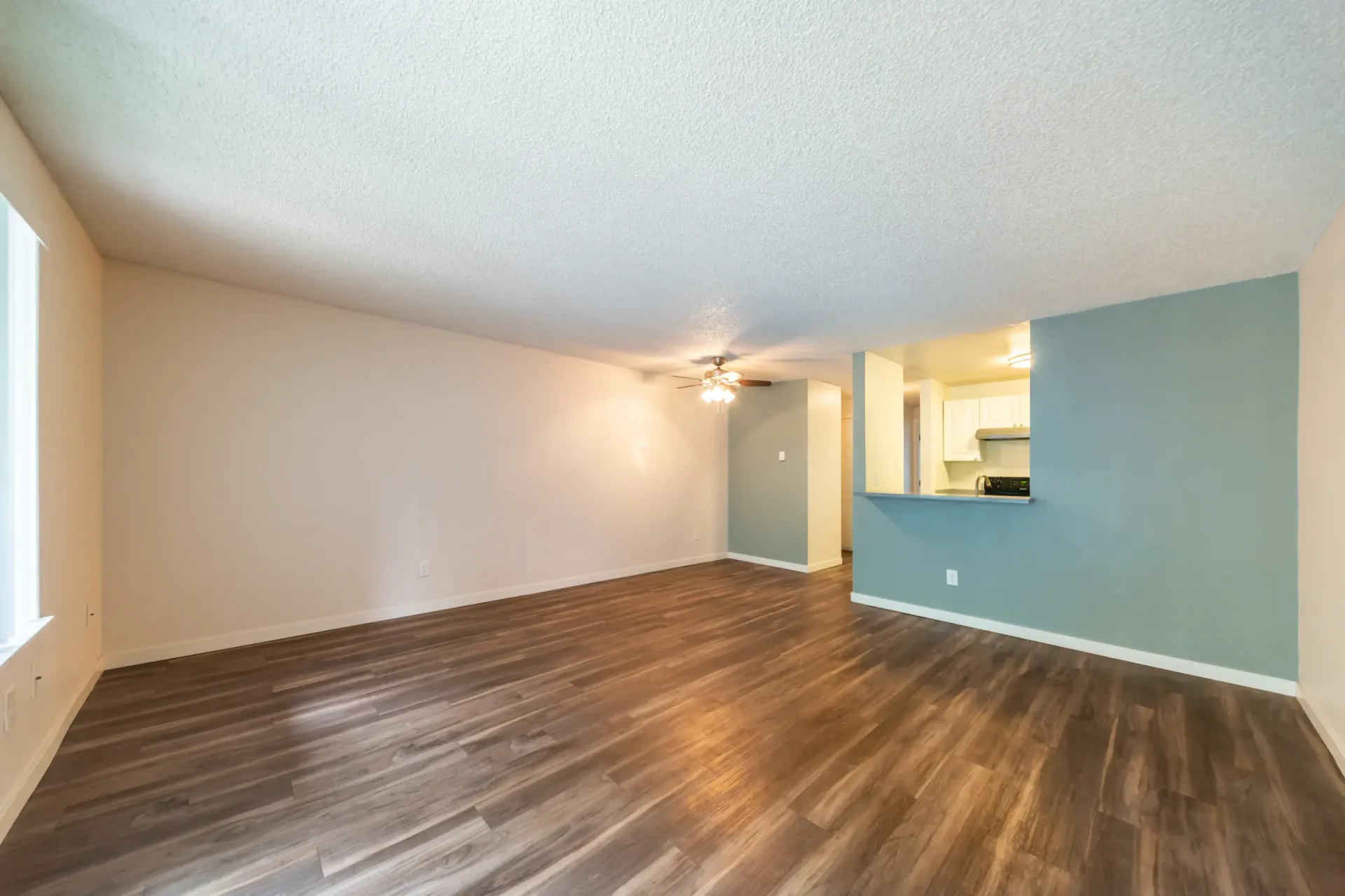 Living room with wood-look flooring and open kitchen pass-through.