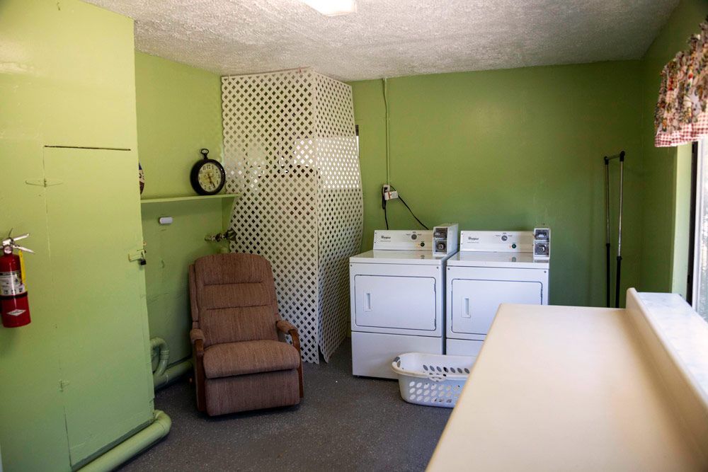 Laundry room with green walls, white appliances, recliner, and decorative screen.
