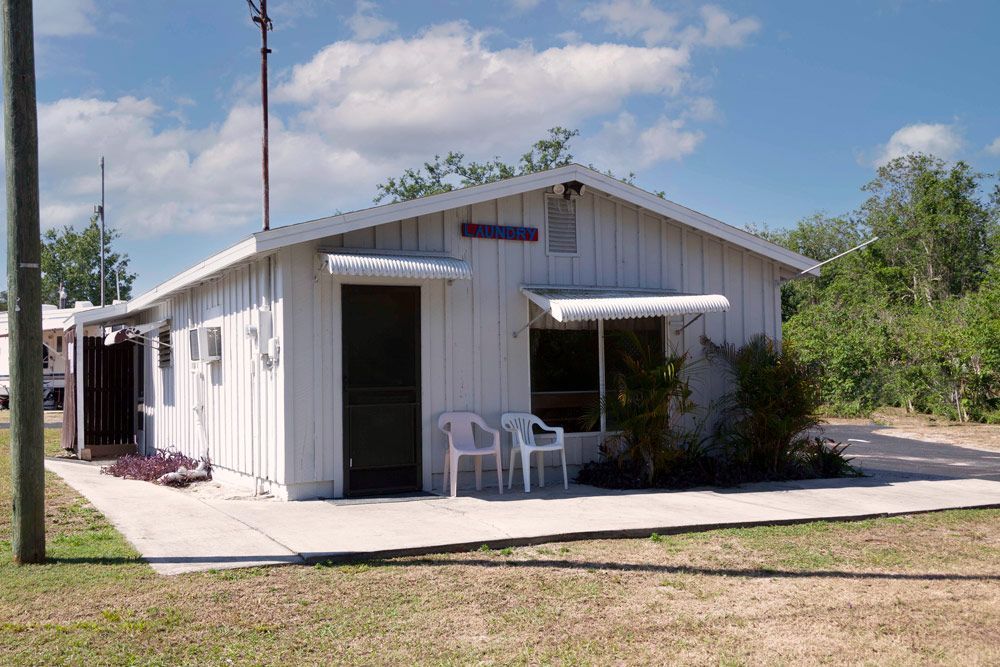 White building with awnings over door and window, two chairs on patio.