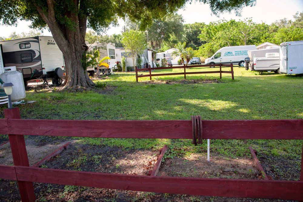 Campground scene with RVs and a red wooden fence.