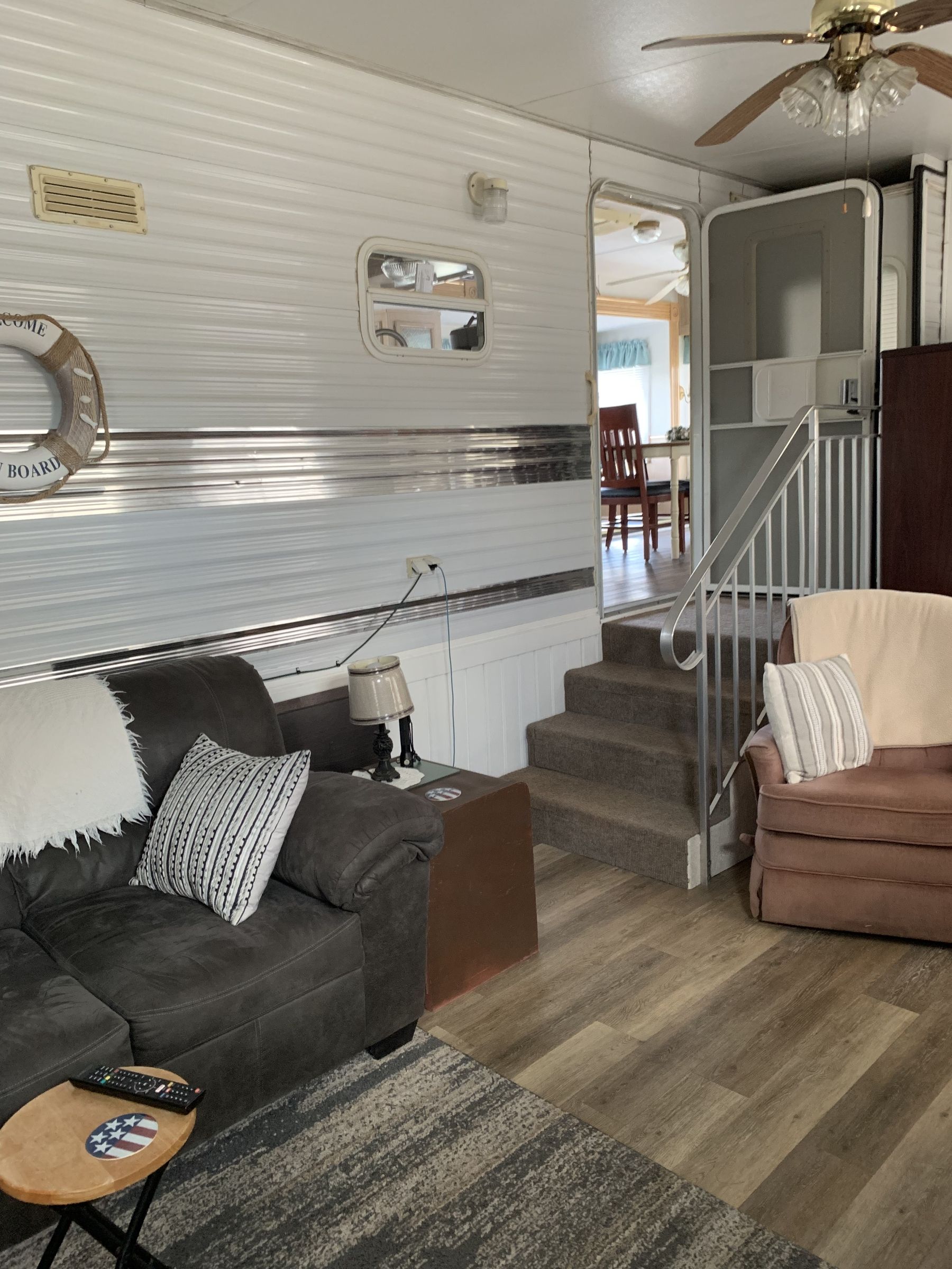 Living room with gray sofa, chair, and wood-look flooring; steps to doorway.
