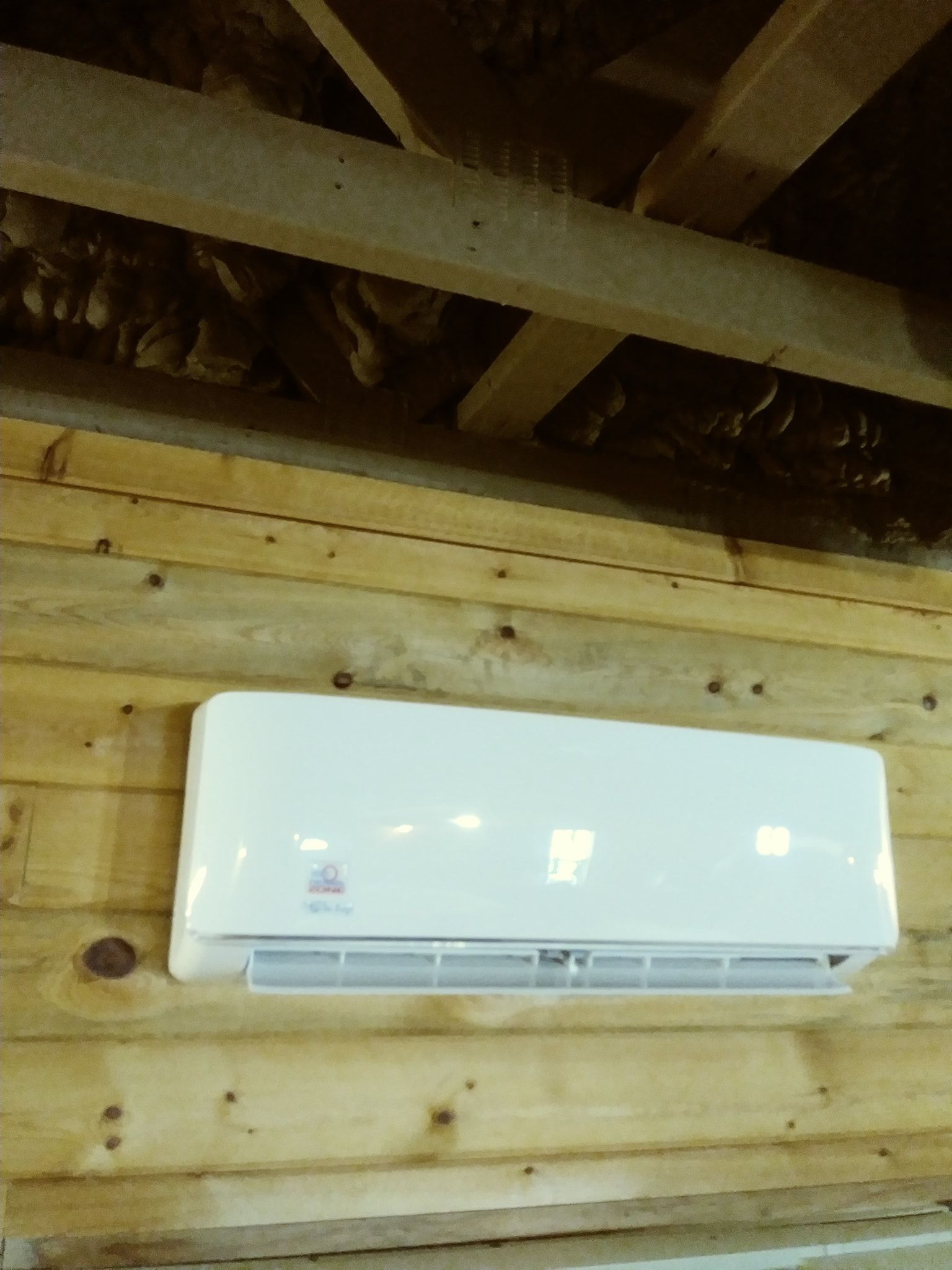 a white air conditioner is mounted on a wooden wall