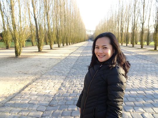 A woman in a black jacket is standing on a cobblestone road