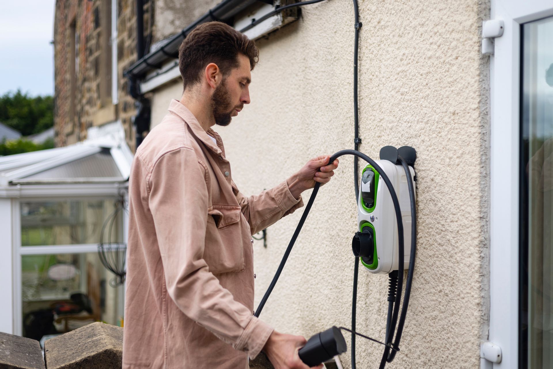 Young male adult unravelling wire on charging station 
