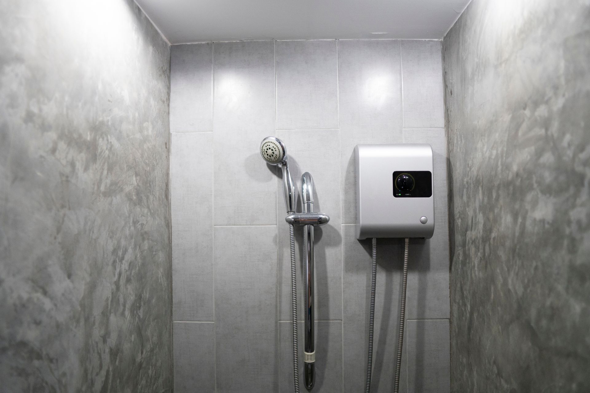 A bathroom with a shower head and a water heater.