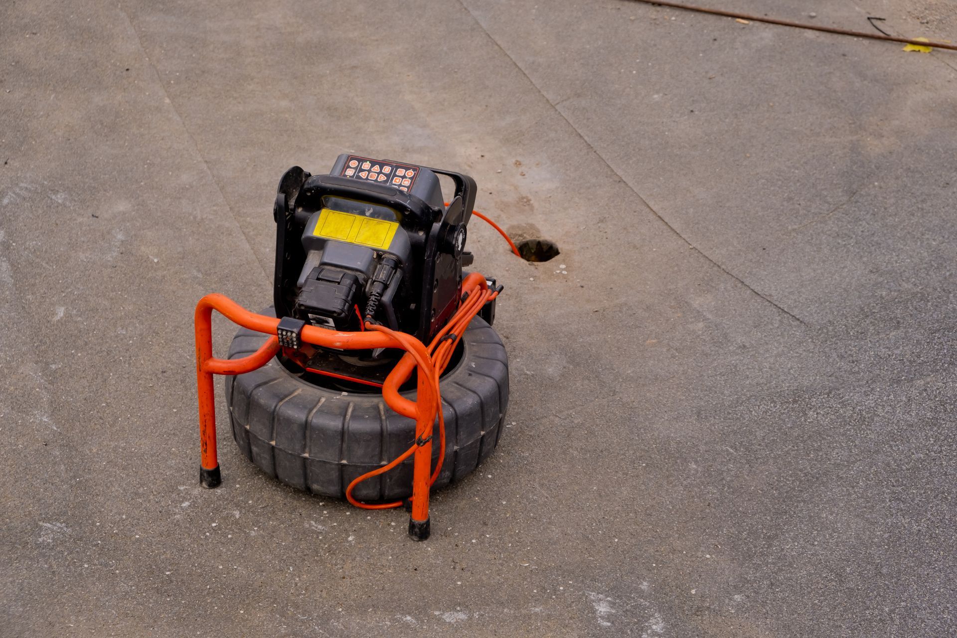 A drain camera is sitting on the ground next to a tire.