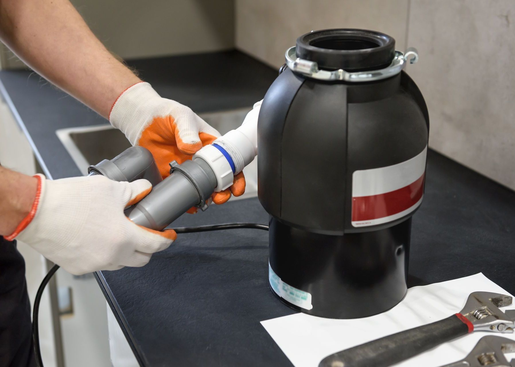 A man is fixing a garbage disposal in a kitchen.