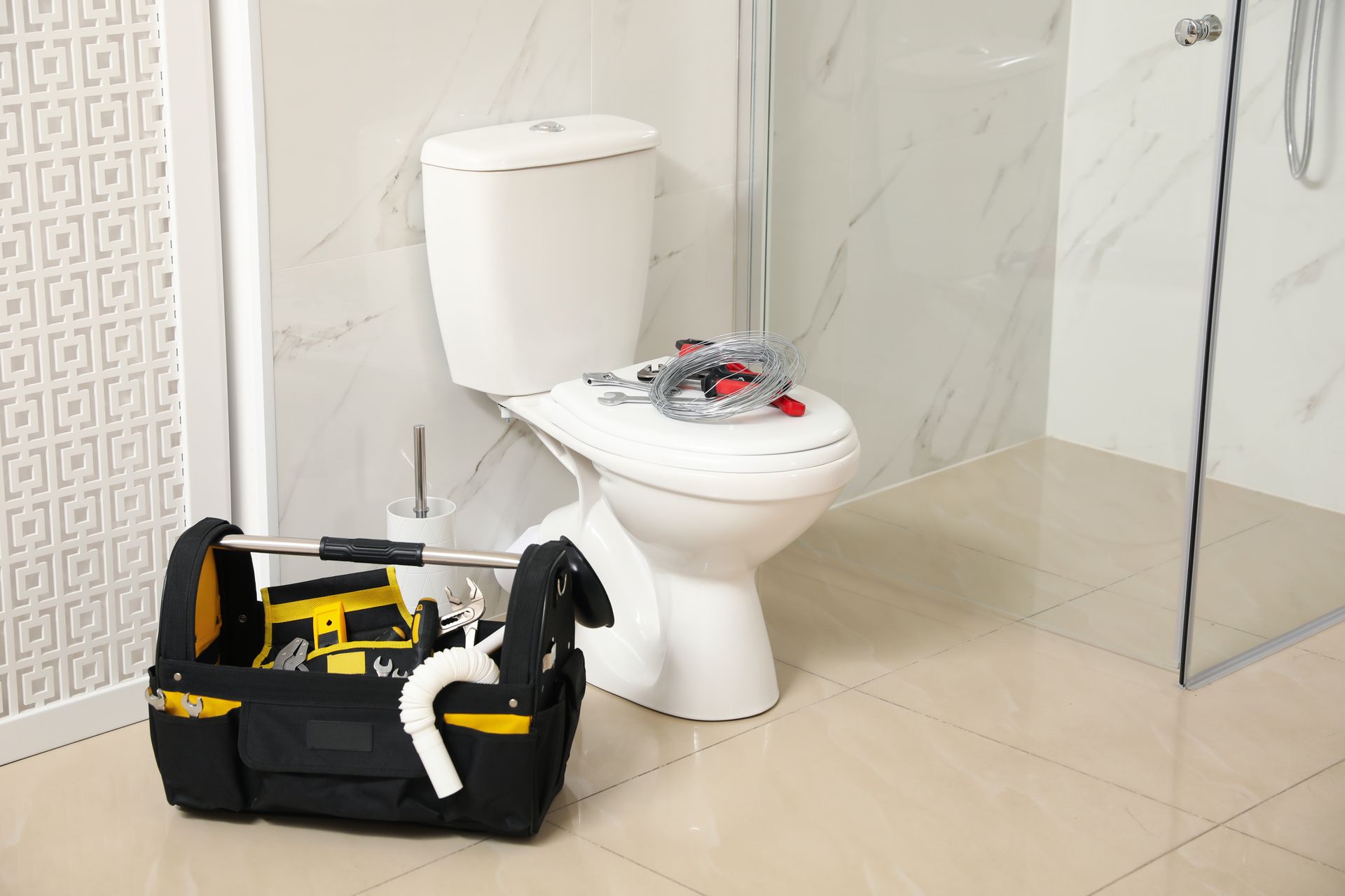 A tool bag is sitting next to a toilet in a bathroom.