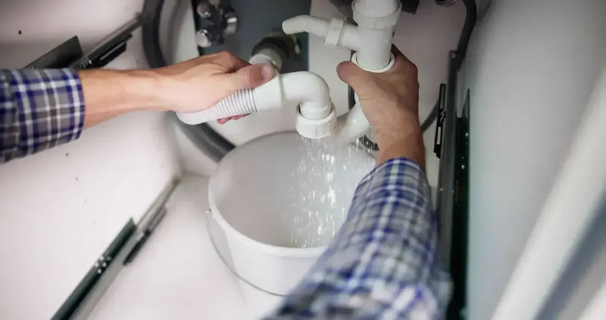 A man is fixing a water heater in a bathroom.