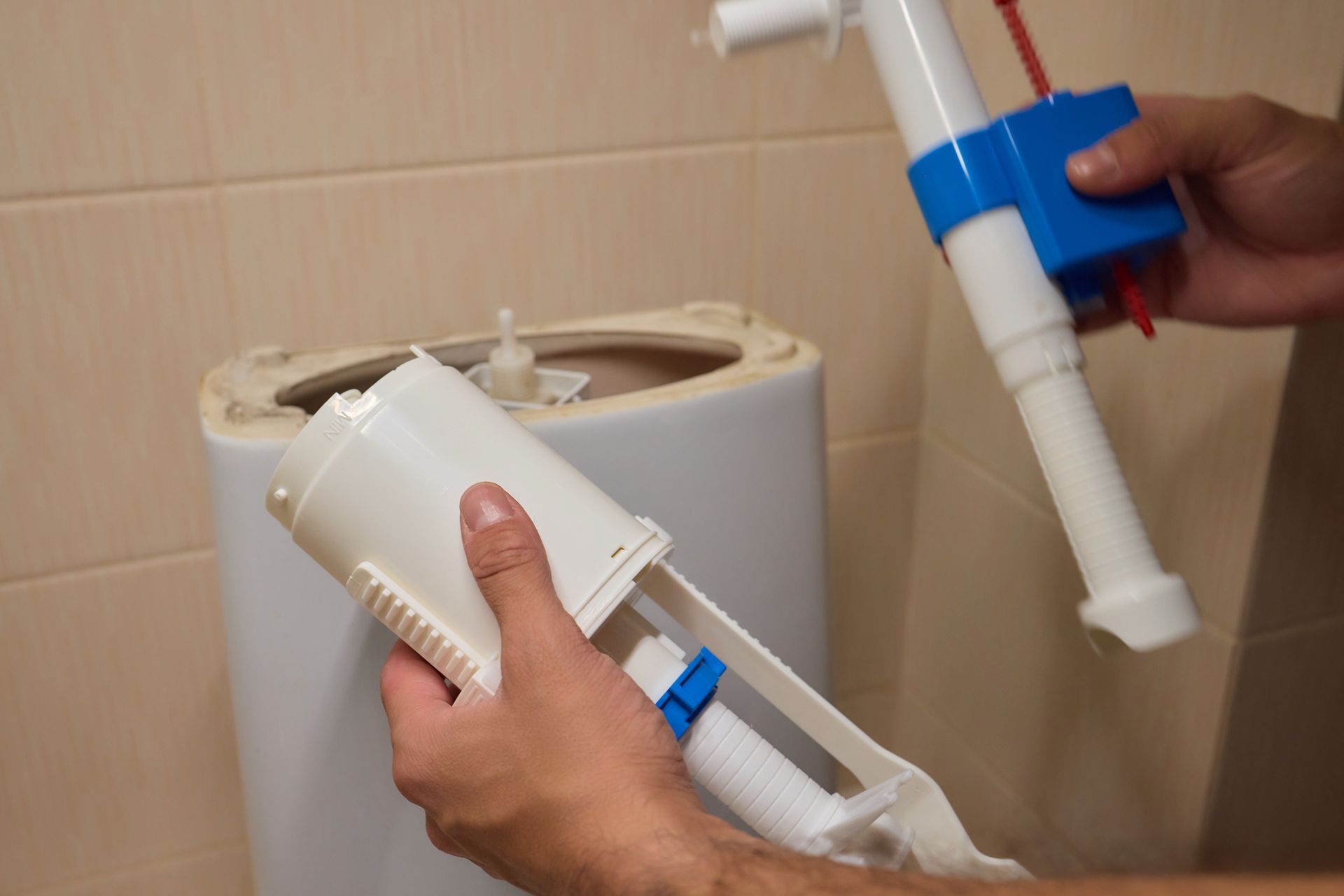 A person is fixing a toilet in a bathroom.