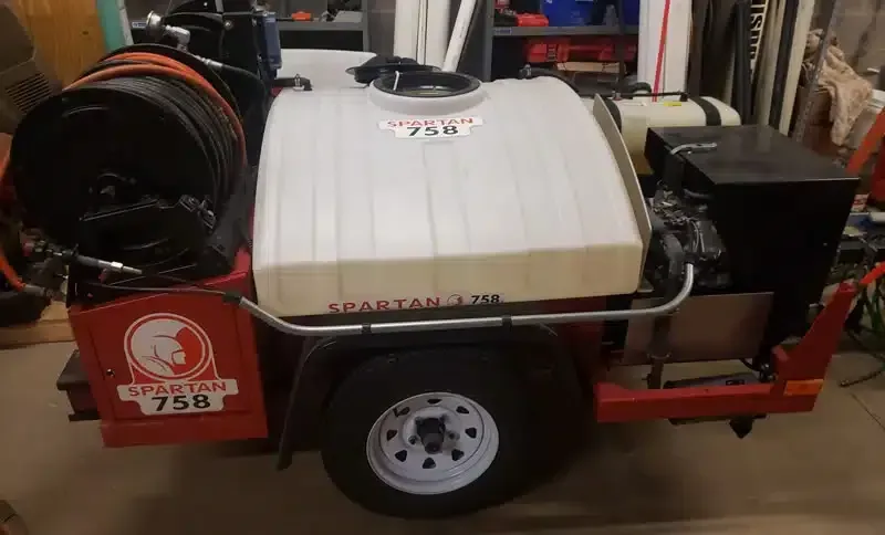 A trailer with a hose attached to it is sitting in a garage.