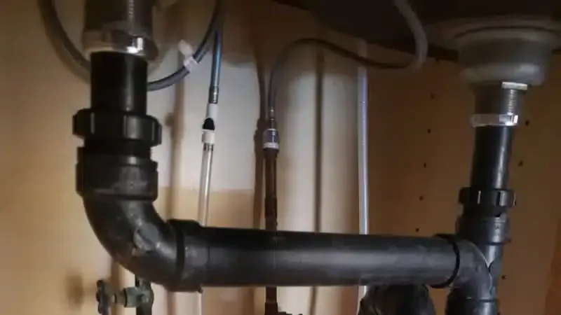 A close up of a sink with a lot of pipes underneath it.