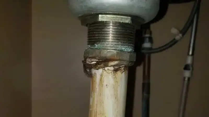 A close up of a pipe under a sink in a bathroom.