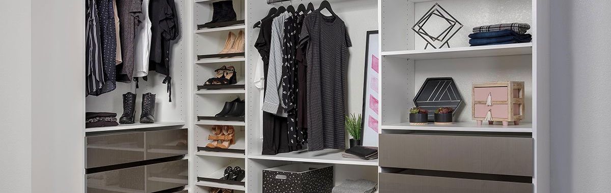 a white and mercury finish closet system filled with clothes, drawers and shoes