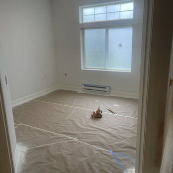 An empty room with a window and a piece of paper on the floor.