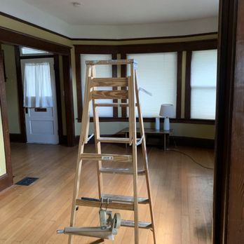 A wooden ladder is sitting in the middle of an empty room.