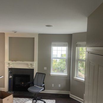 A living room with a fireplace , chair , and windows.