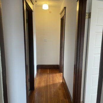 A hallway with hardwood floors and white walls in a house.