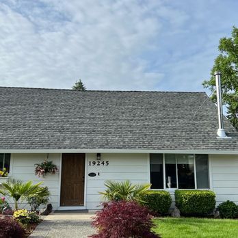A white house with a gray roof and a chimney.