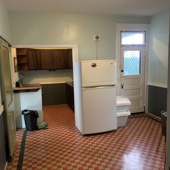 A kitchen with a refrigerator and a checkered floor.