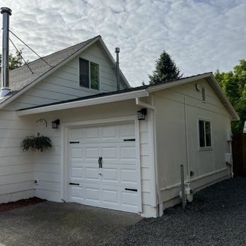 A white house with a garage and a chimney on the roof.