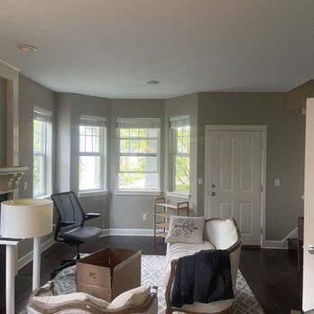 A living room with a couch , chair , lamp and a box on the floor.