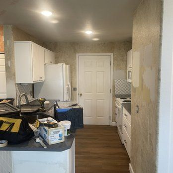 A kitchen with white cabinets , a refrigerator , a sink , and a door.