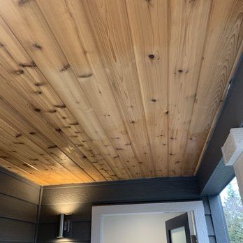 A wooden ceiling in a room with a door.