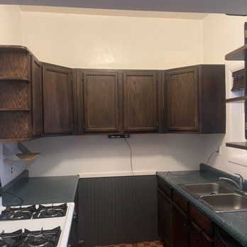 A kitchen with a stove , sink , and cabinets.