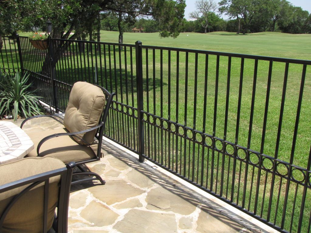 A fence surrounds a patio with a table and chairs.