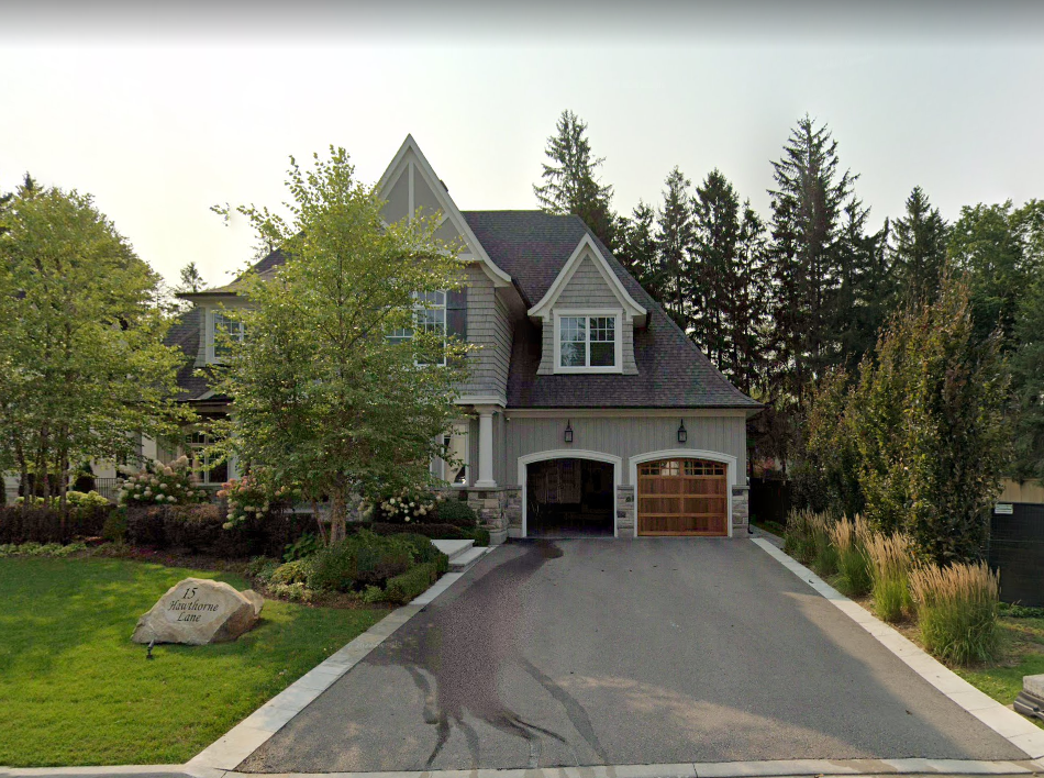 An aerial view of a large house with a driveway leading to it surrounded by trees.