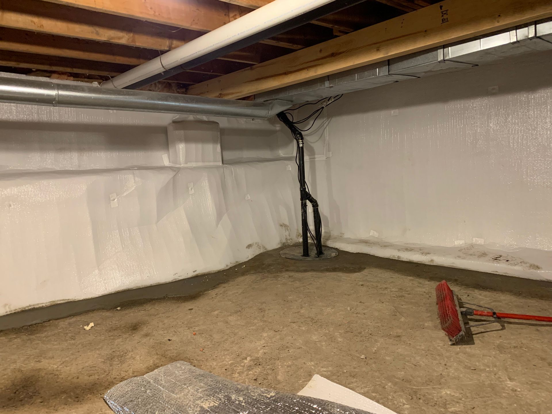 A basement with a white wall and a red broom.