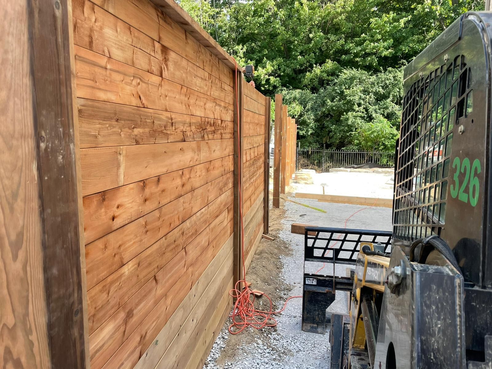 A wooden fence is being built next to a skid steer.