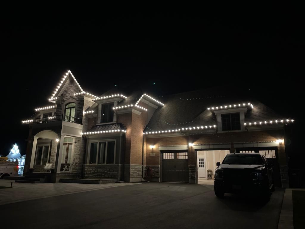 A large house with christmas lights on it is lit up at night.