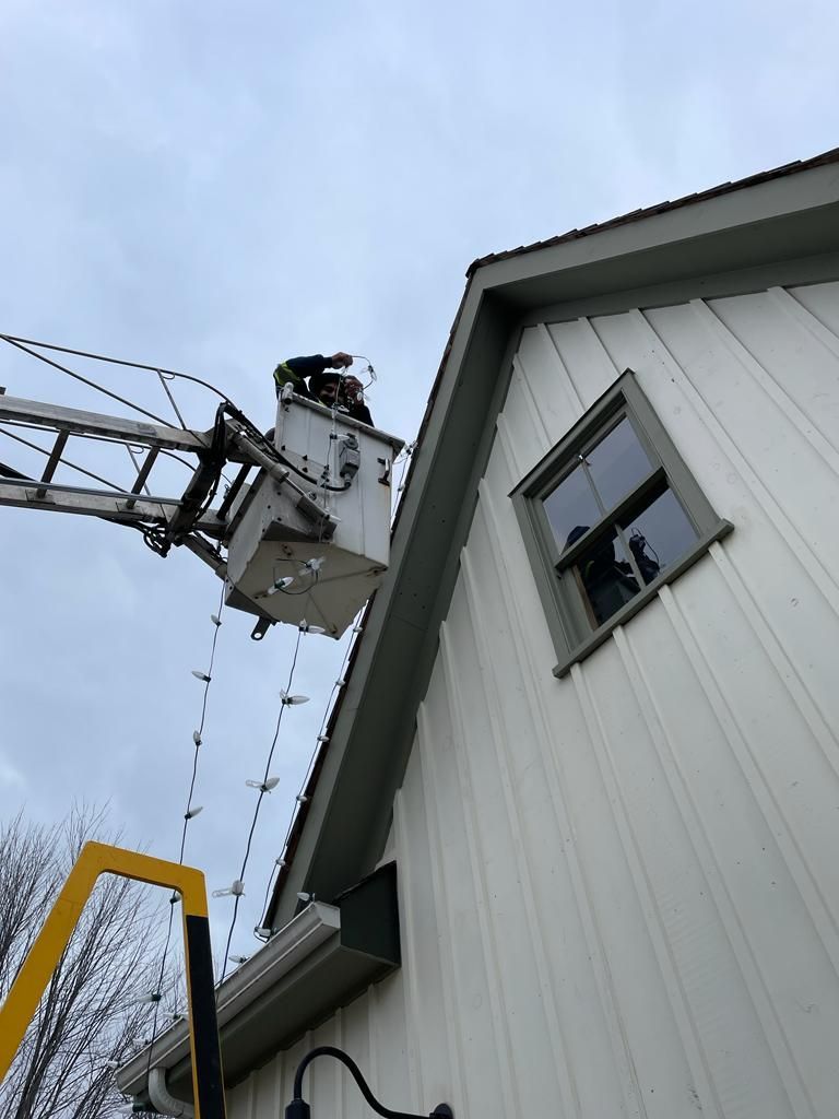 A man in a bucket is working on the roof of a house.