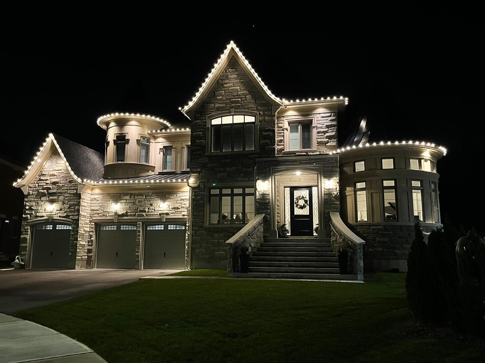 A large house is lit up at night with christmas lights