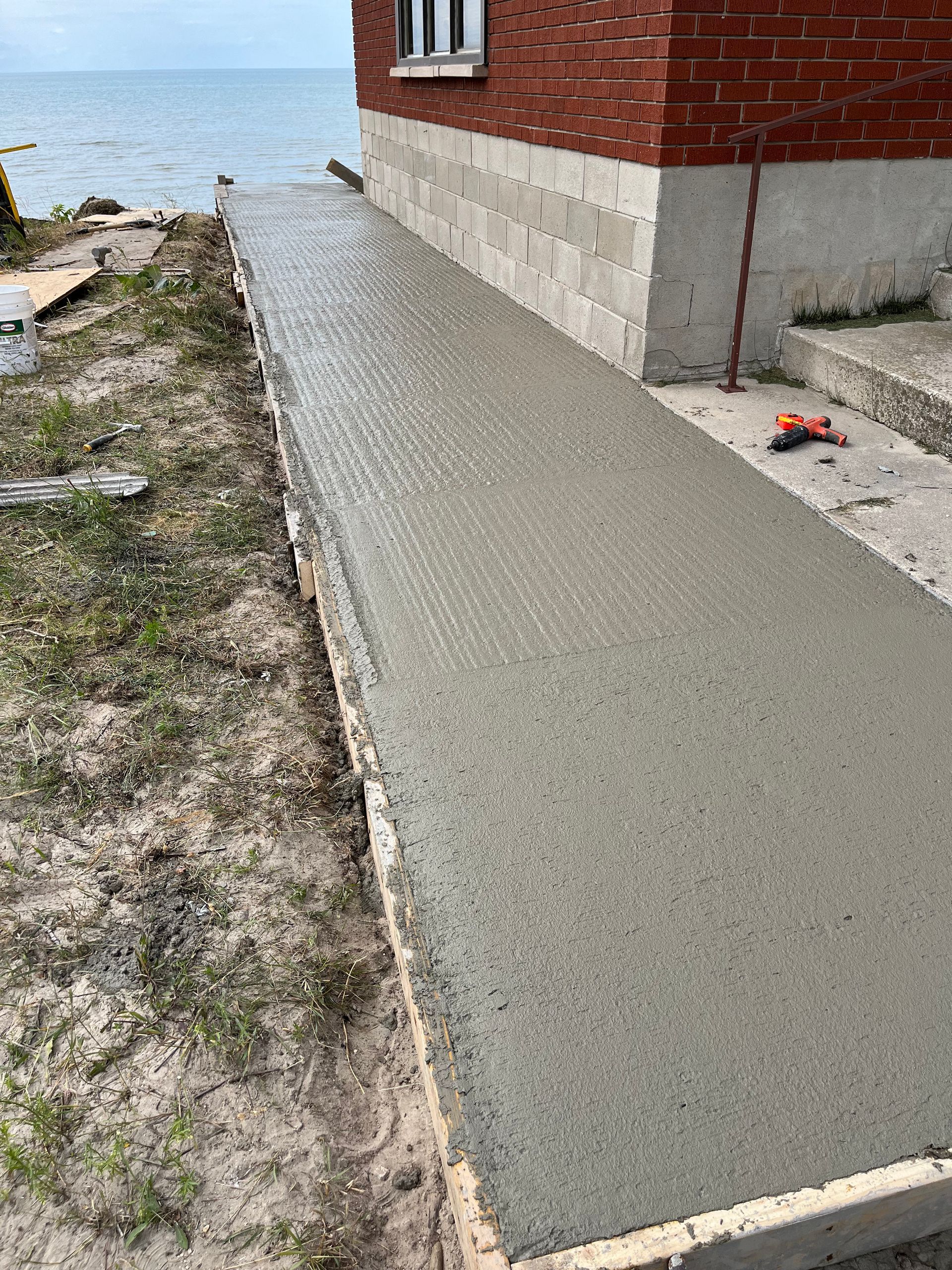 A concrete walkway is being built next to a brick building.