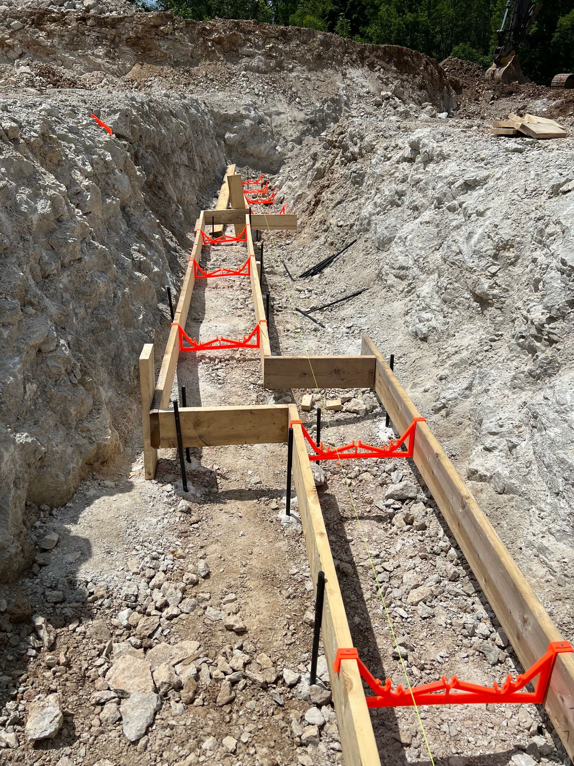 A construction site with a row of wooden beams in the dirt.