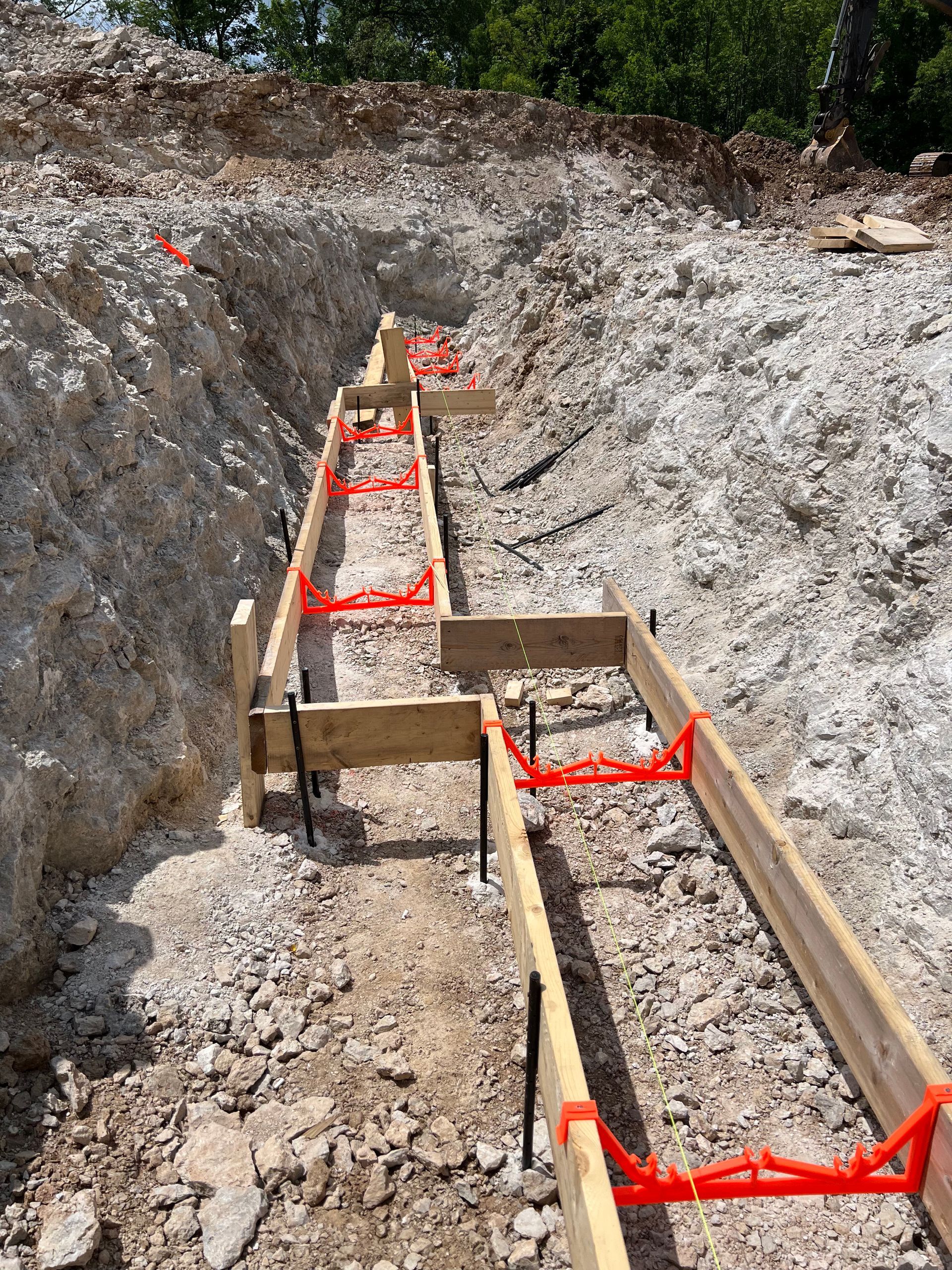 A construction site with a row of wooden beams in the dirt.