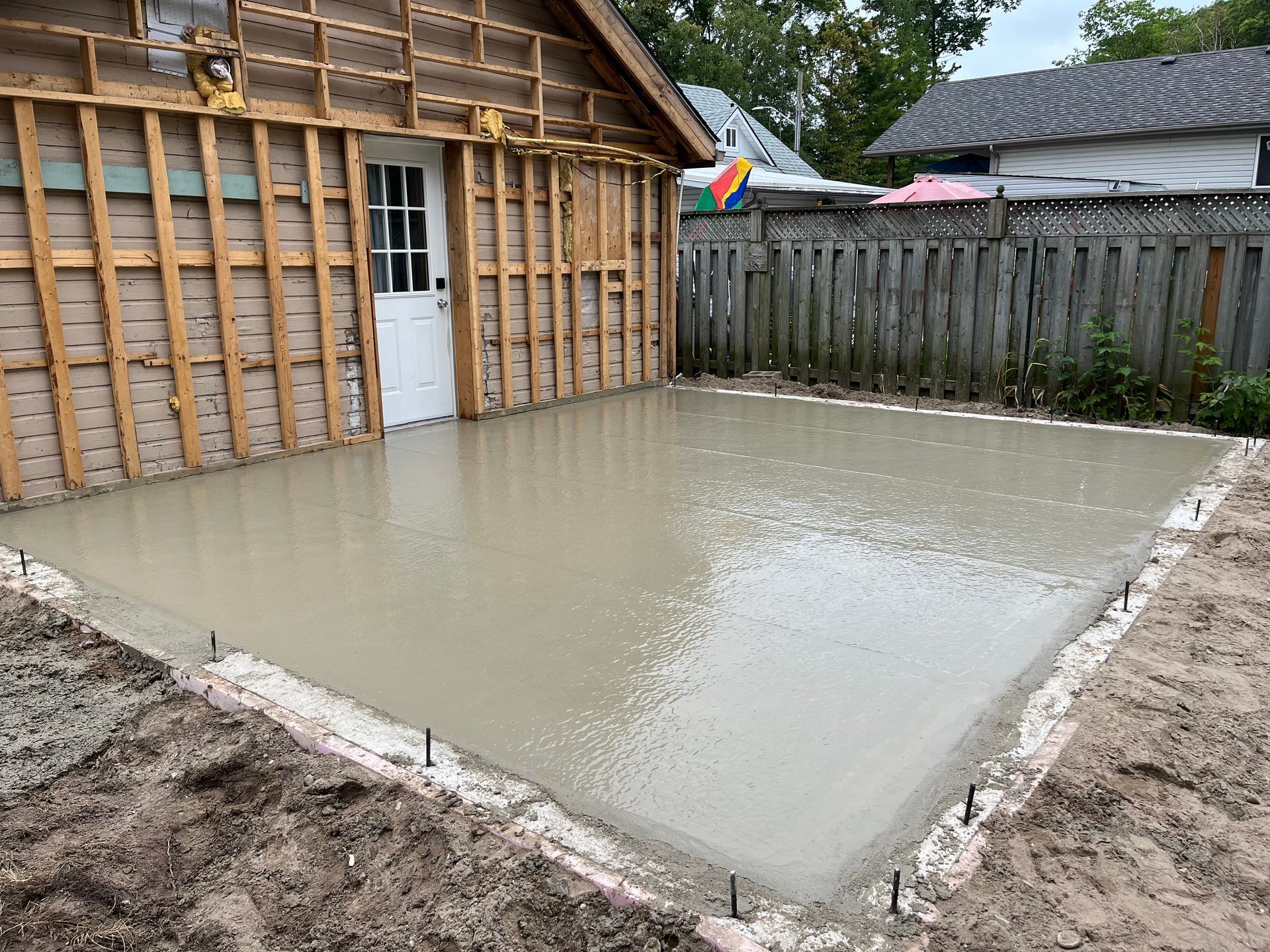 A concrete floor is being poured in front of a house.