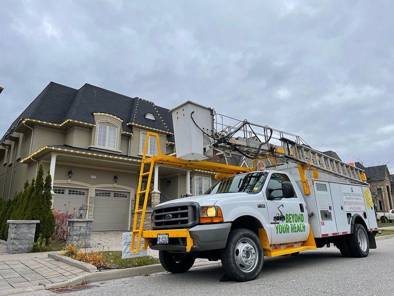 A white truck with a yellow ladder is parked in front of a house.