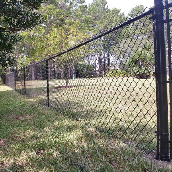 A chain link fence surrounds a lush green field.