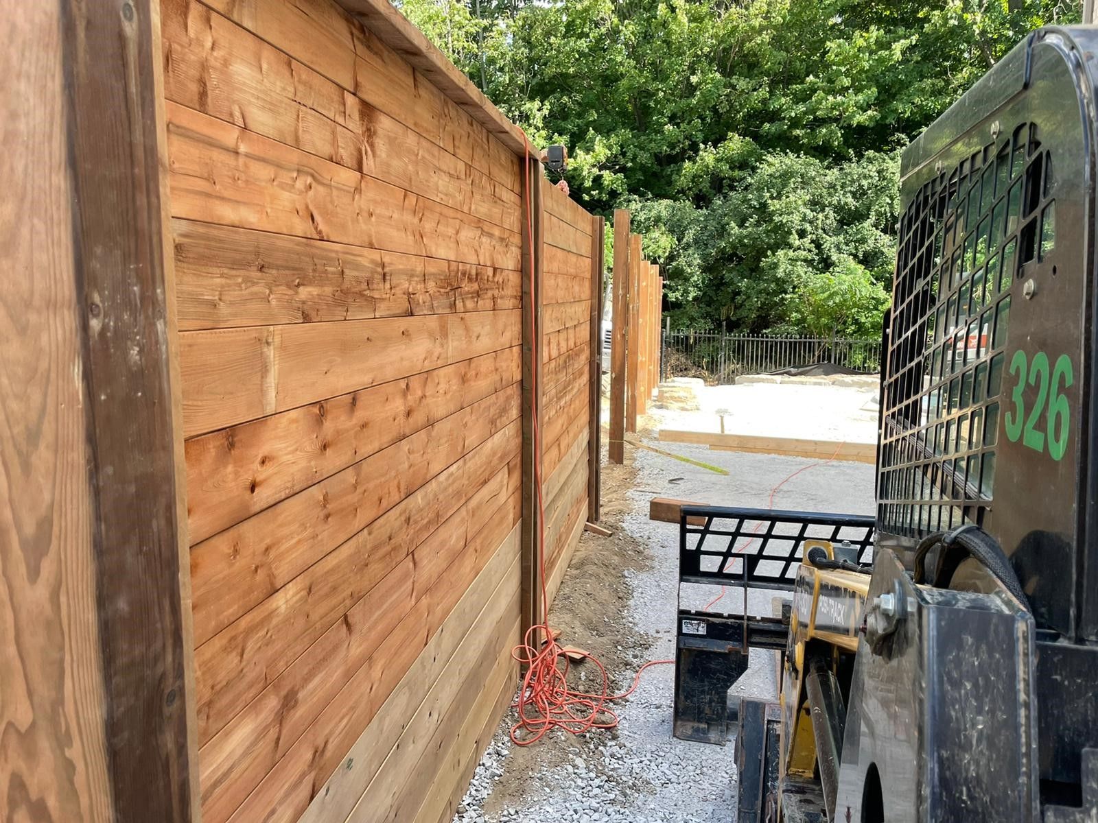 A wooden fence is being built next to a bulldozer.