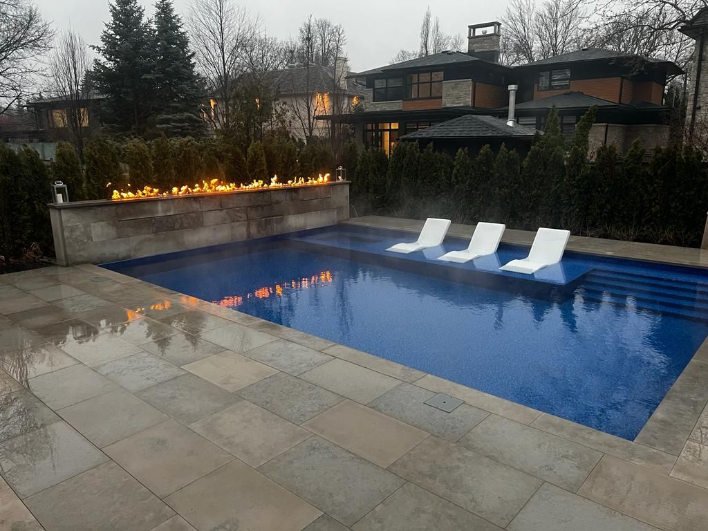 A large swimming pool with three lounge chairs in it