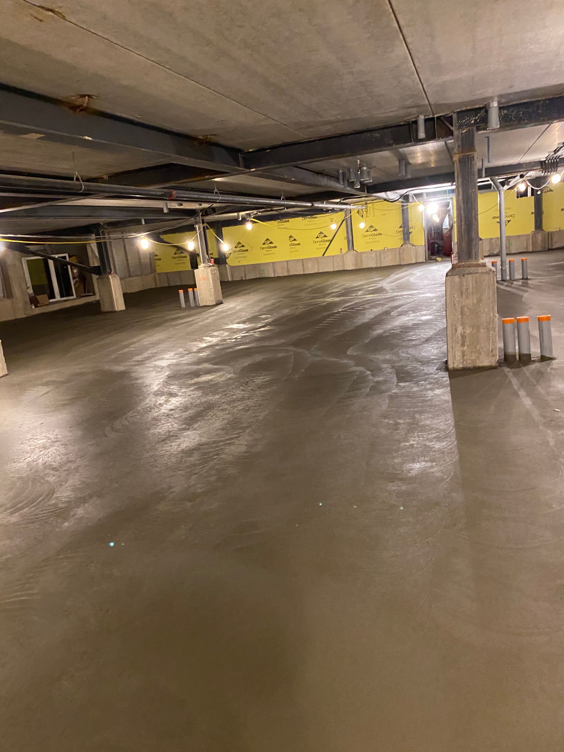 An empty parking garage with a concrete floor and yellow walls.