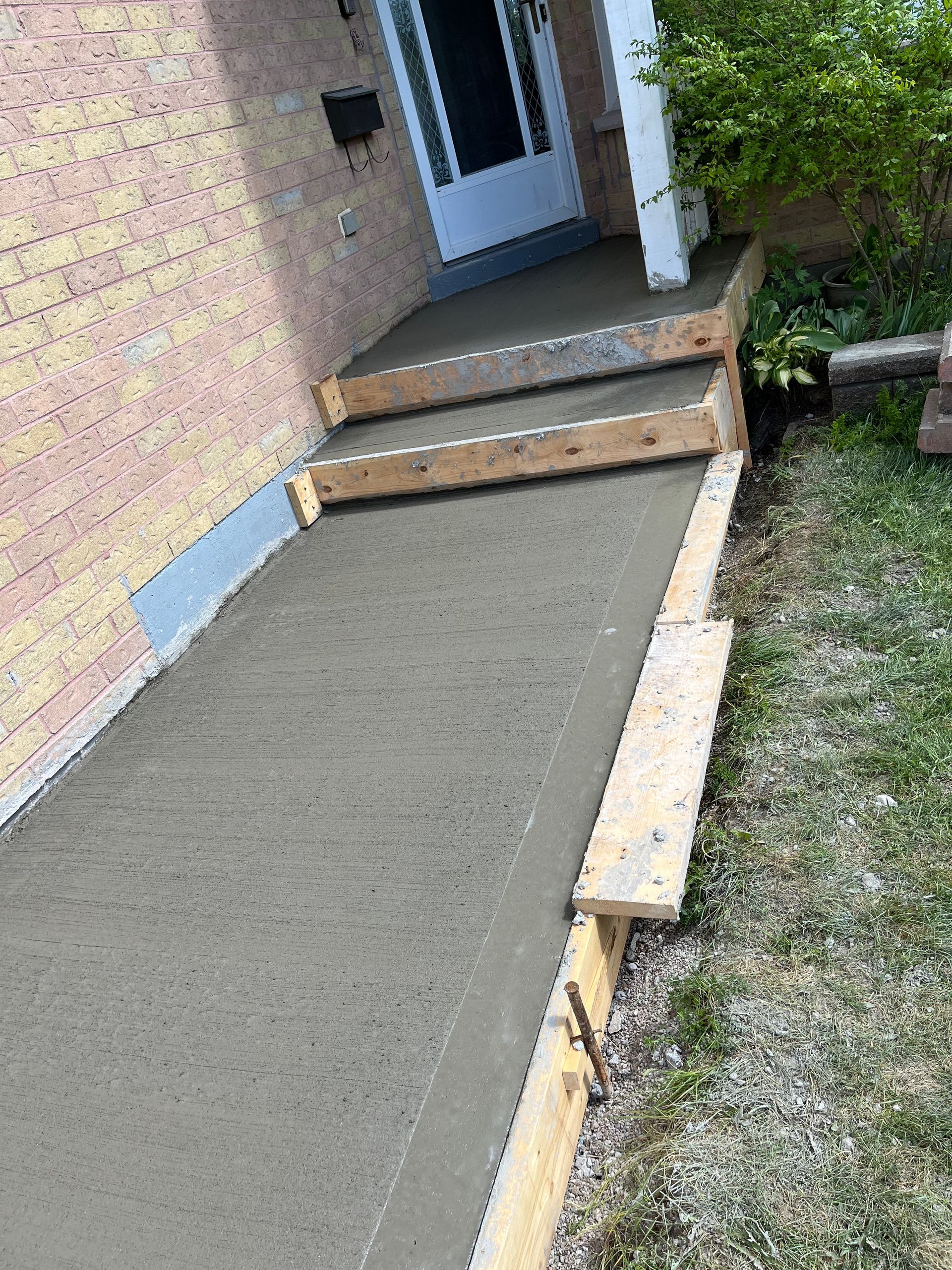 A concrete walkway is being built in front of a house.