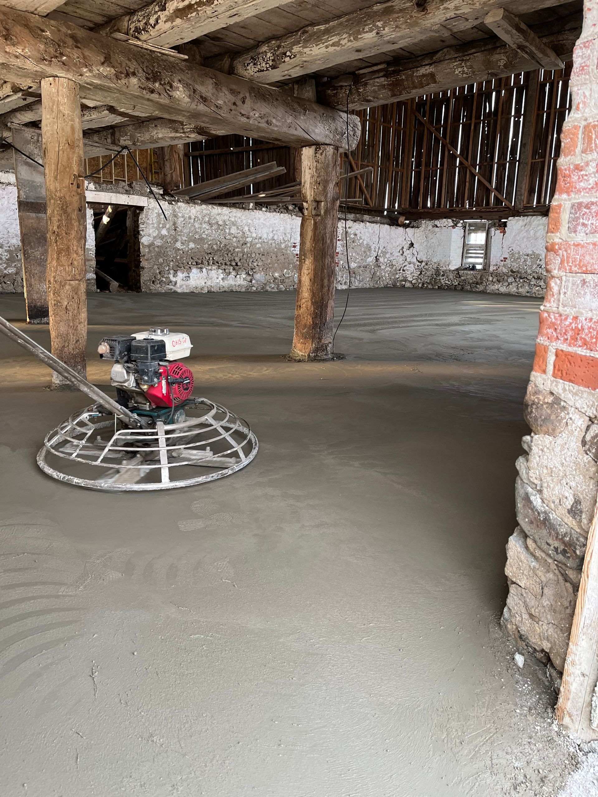 A person is using a trowel on a concrete floor.