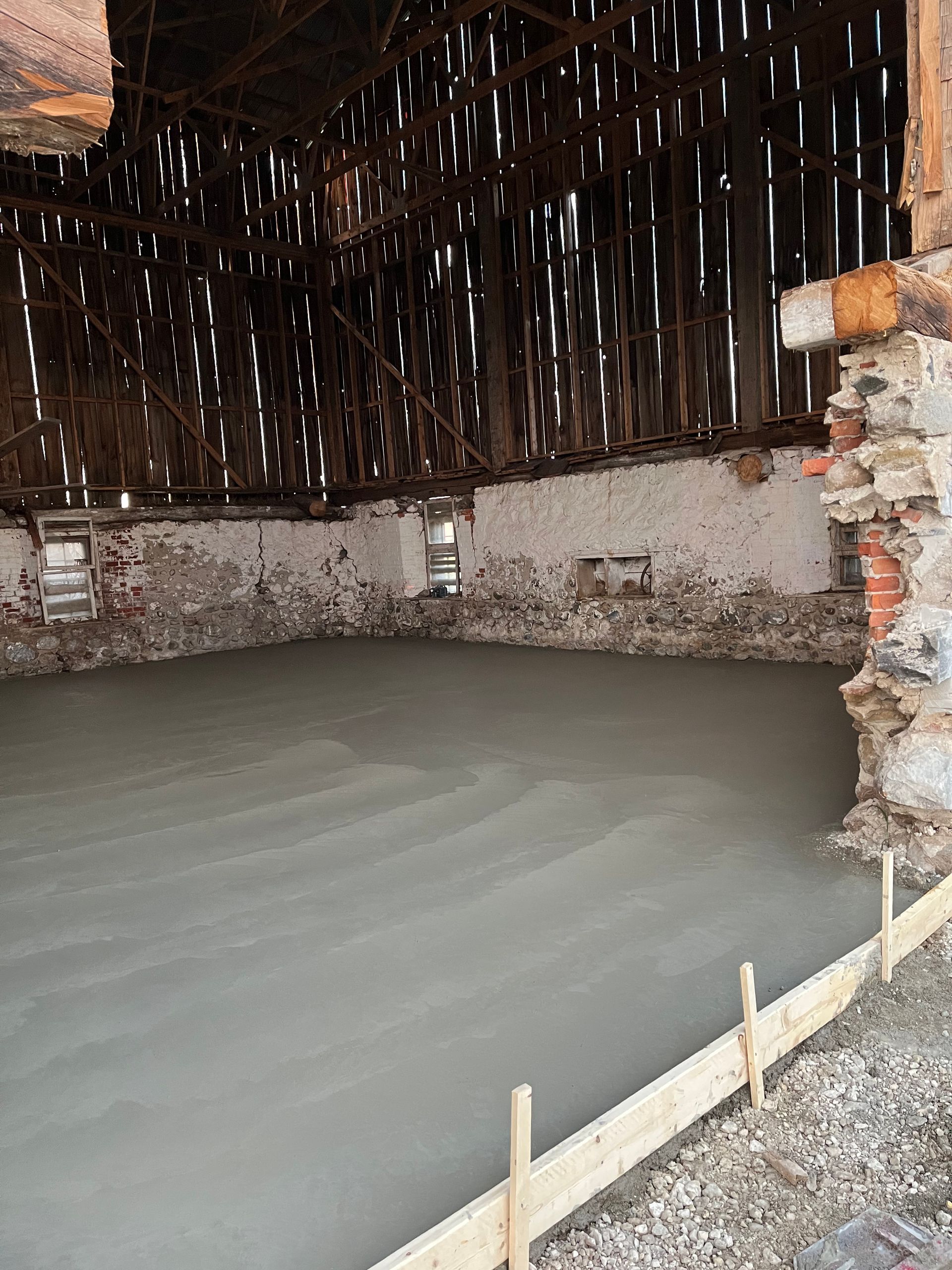 A concrete floor is being poured in a barn.